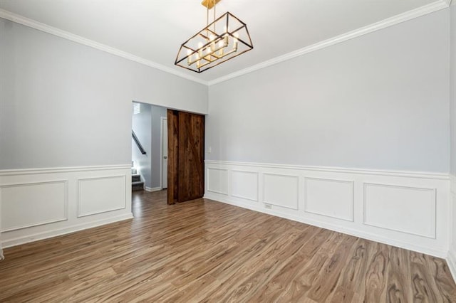 unfurnished dining area with stairway, wood finished floors, ornamental molding, wainscoting, and a notable chandelier