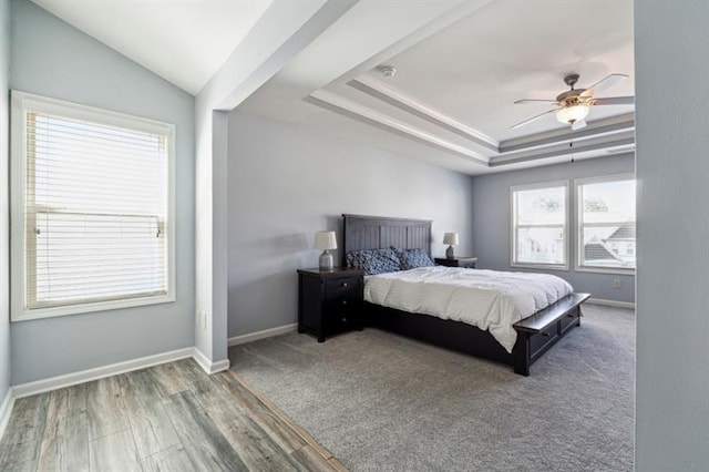 bedroom featuring a raised ceiling, wood finished floors, a ceiling fan, and baseboards