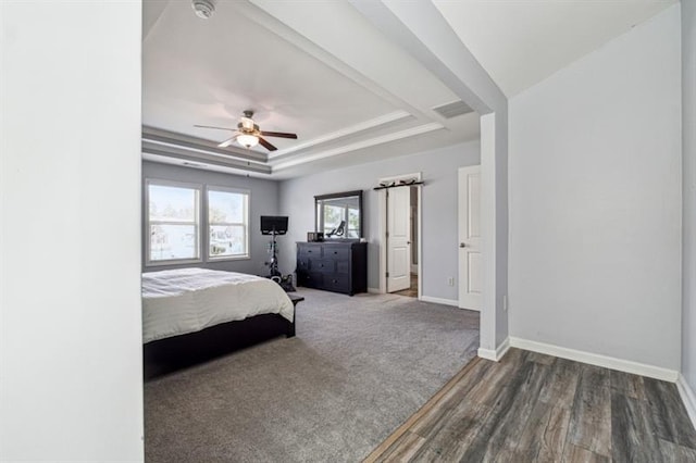 bedroom with visible vents, wood finished floors, baseboards, and a tray ceiling