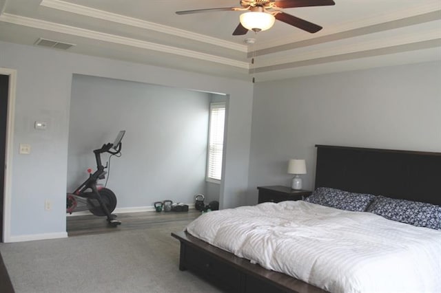 bedroom featuring baseboards, ornamental molding, a tray ceiling, and visible vents