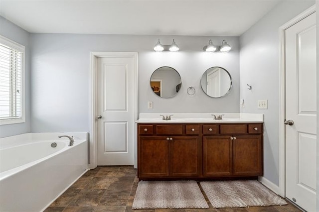 bathroom featuring a garden tub, a wealth of natural light, double vanity, and stone finish flooring