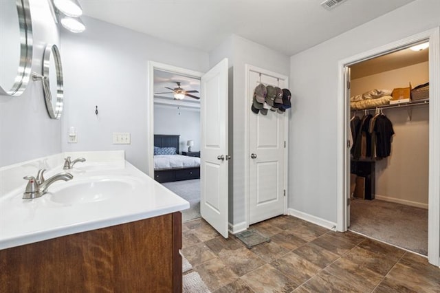 bathroom with a sink, ceiling fan, double vanity, baseboards, and ensuite bath
