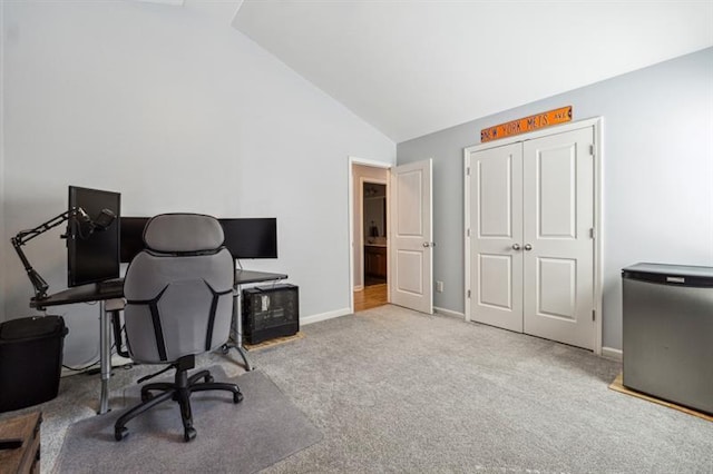 carpeted office space featuring vaulted ceiling and baseboards