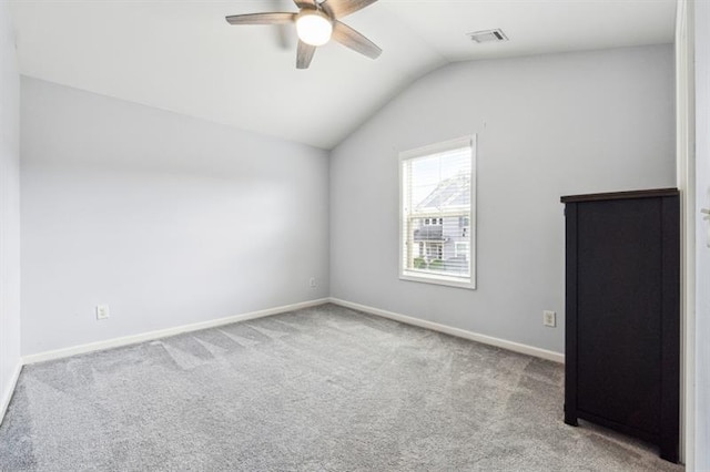 carpeted empty room with vaulted ceiling, visible vents, baseboards, and ceiling fan