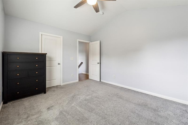 unfurnished bedroom with lofted ceiling, a ceiling fan, baseboards, and light colored carpet