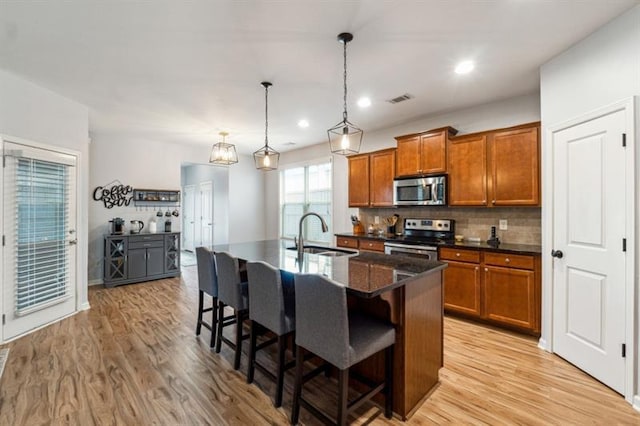 kitchen featuring brown cabinets, visible vents, appliances with stainless steel finishes, and a sink