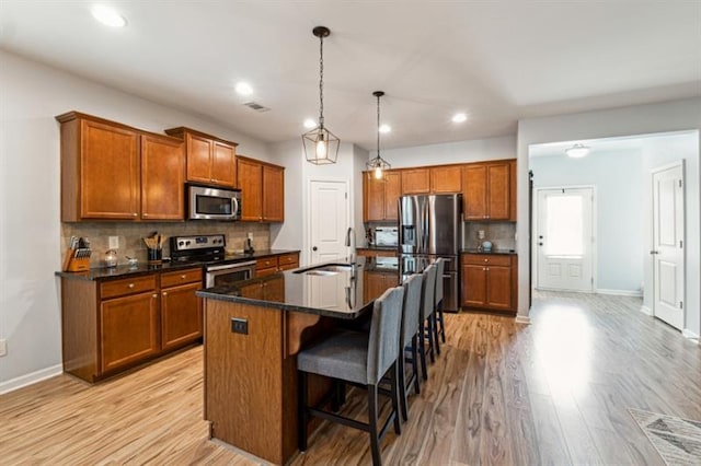 kitchen featuring brown cabinets, tasteful backsplash, appliances with stainless steel finishes, and a sink