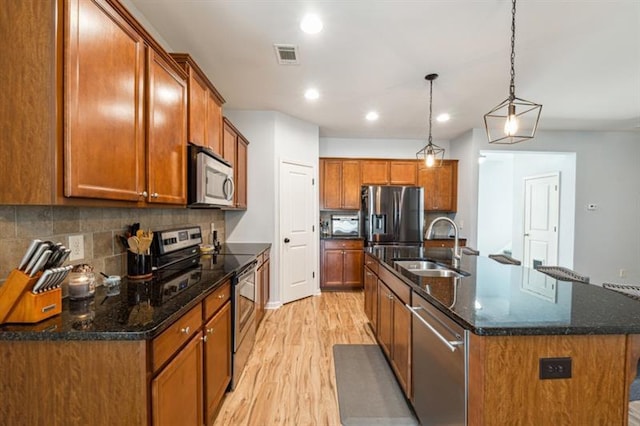 kitchen featuring brown cabinets, light wood-style flooring, stainless steel appliances, and a sink