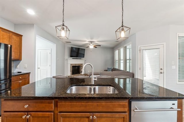kitchen with a sink, open floor plan, ceiling fan, a brick fireplace, and freestanding refrigerator