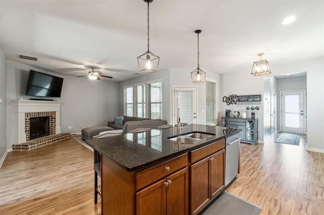kitchen featuring brown cabinetry, stainless steel dishwasher, a sink, and baseboards