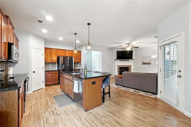 5925 Watersdown Way, Flowery Branch, GA 30542 - kitchen featuring a sink, appliances with stainless steel finishes, a brick fireplace, ceiling fan, and light wood-type flooring