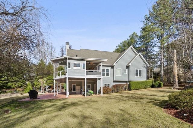 back of house with a sunroom, a yard, a balcony, and a patio