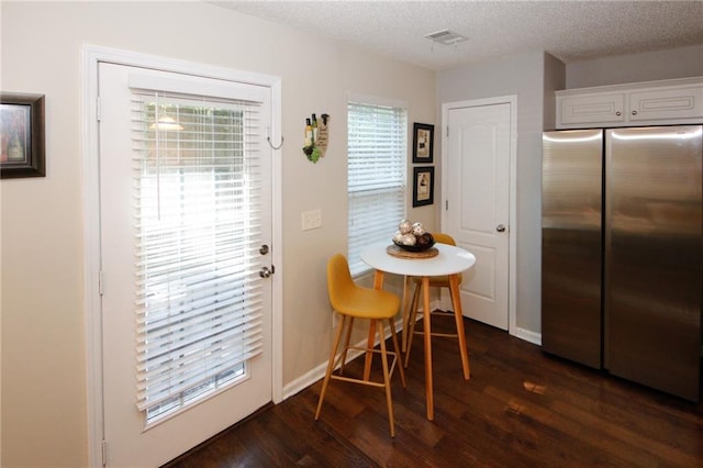 dining space with dark hardwood / wood-style floors and a textured ceiling