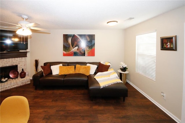 living room featuring dark hardwood / wood-style flooring, a brick fireplace, and ceiling fan