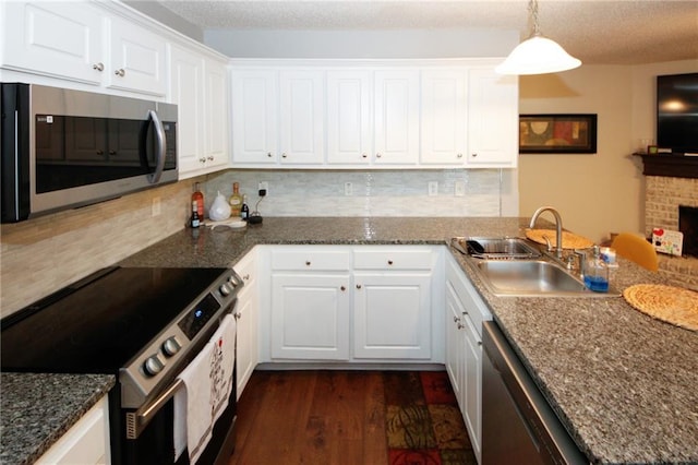 kitchen featuring pendant lighting, sink, stainless steel appliances, white cabinets, and kitchen peninsula