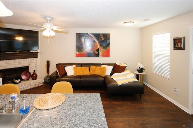 living room featuring ceiling fan, dark hardwood / wood-style flooring, sink, and a brick fireplace