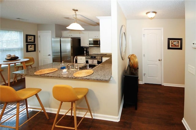 kitchen with decorative light fixtures, a breakfast bar area, white cabinets, and appliances with stainless steel finishes