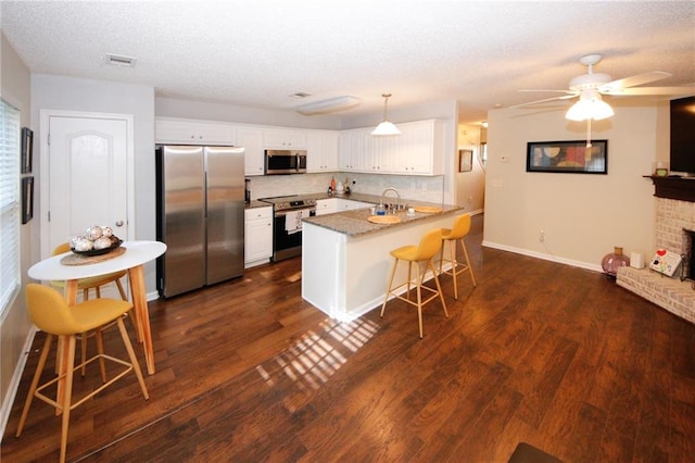 kitchen featuring a kitchen bar, sink, white cabinetry, kitchen peninsula, and stainless steel appliances