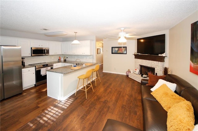 kitchen with pendant lighting, a breakfast bar, white cabinets, and appliances with stainless steel finishes