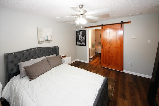 bedroom with ceiling fan, dark wood-type flooring, a barn door, and a textured ceiling