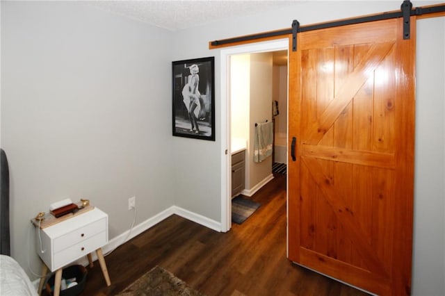 hallway with dark wood-type flooring, a barn door, and a textured ceiling