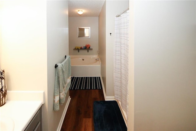 bathroom featuring vanity, a washtub, a textured ceiling, and hardwood / wood-style flooring