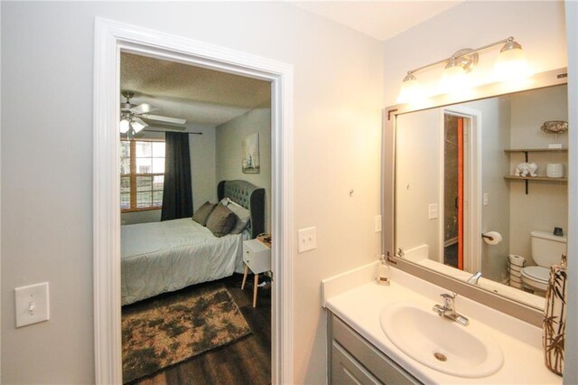 bathroom featuring wood-type flooring, vanity, ceiling fan, and toilet