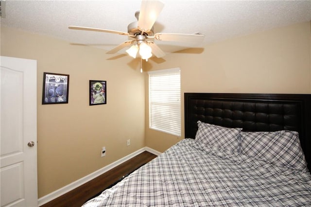 bedroom with ceiling fan, a textured ceiling, and dark hardwood / wood-style flooring