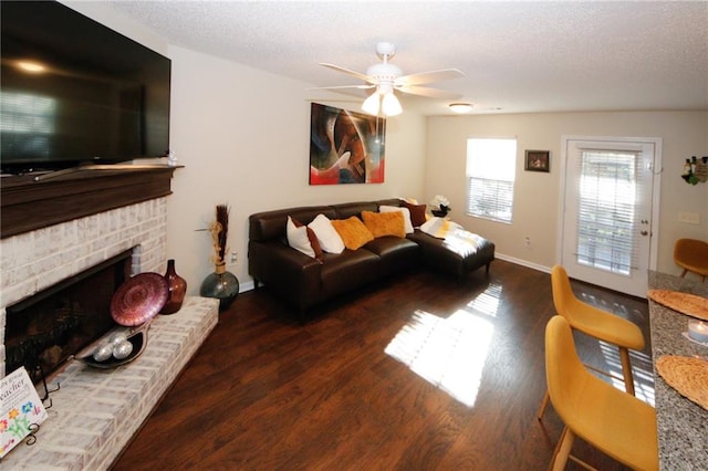 living room with dark hardwood / wood-style flooring, a textured ceiling, ceiling fan, and a fireplace