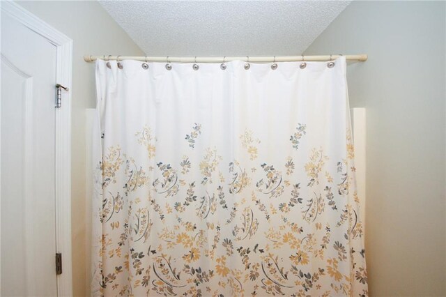 bathroom with curtained shower and a textured ceiling