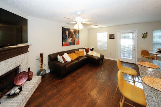 living room with dark hardwood / wood-style flooring, a brick fireplace, a textured ceiling, and ceiling fan