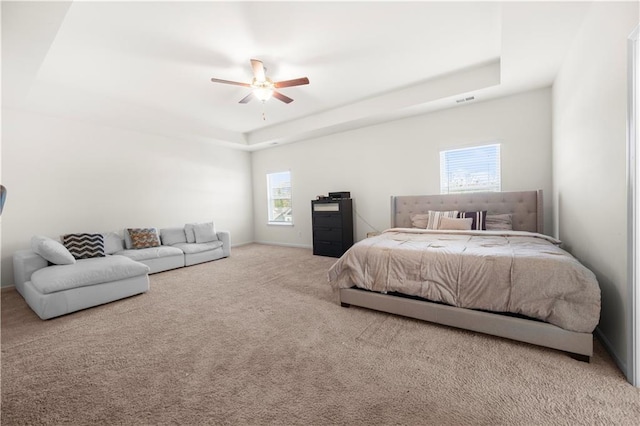 carpeted bedroom featuring a raised ceiling and ceiling fan