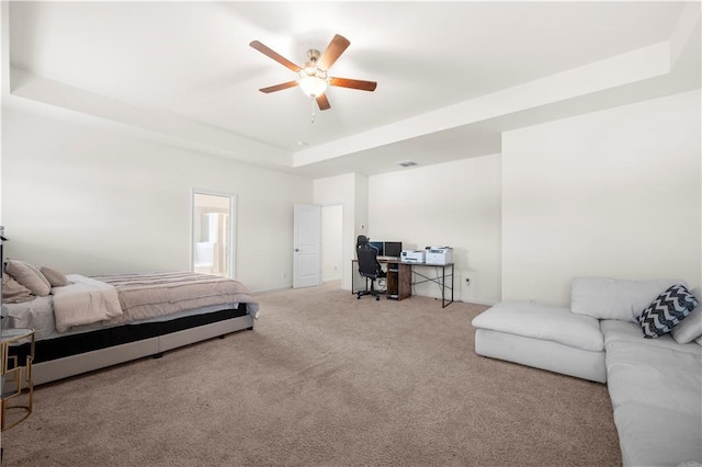 carpeted bedroom featuring a tray ceiling and ceiling fan