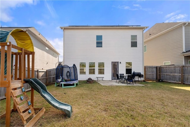 rear view of property featuring a yard, a playground, a patio area, and a trampoline