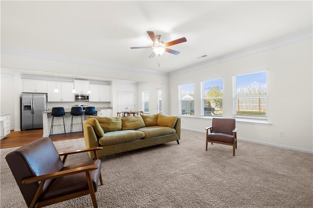 living room featuring crown molding, ceiling fan, and carpet