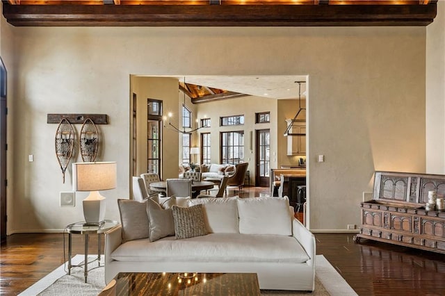 living area with dark wood finished floors, a high ceiling, beamed ceiling, and baseboards