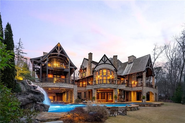 rear view of house featuring stone siding and a balcony