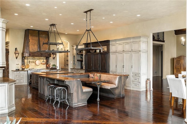 kitchen with a spacious island, dark wood-style floors, a kitchen breakfast bar, dark stone counters, and pendant lighting