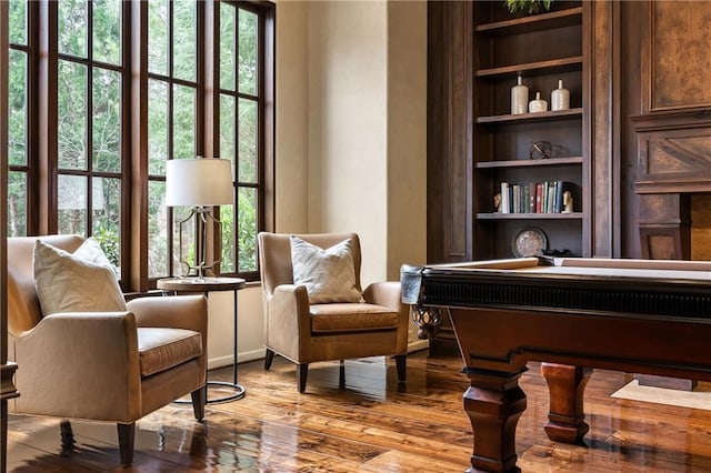 sitting room with baseboards, light wood-type flooring, and built in features