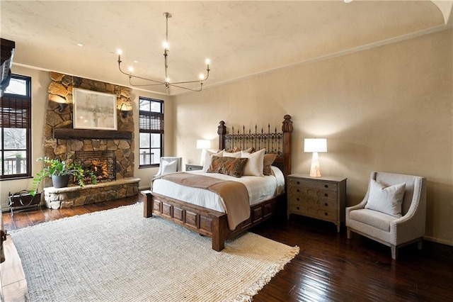 bedroom with dark wood-style floors, a fireplace, baseboards, and an inviting chandelier