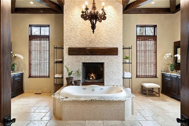 full bathroom featuring a garden tub, baseboards, stone tile flooring, and vanity