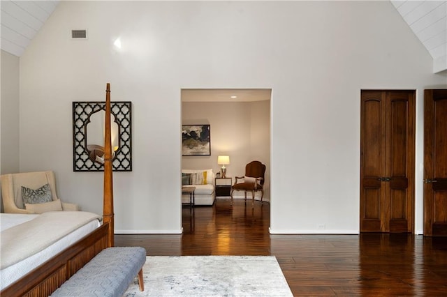 interior space with high vaulted ceiling, dark wood-style flooring, visible vents, and baseboards