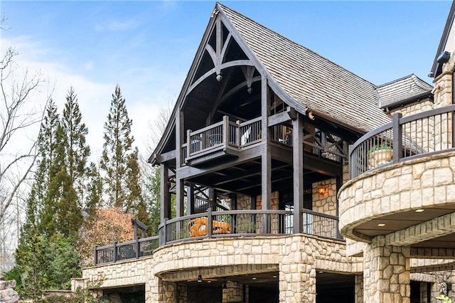 back of property featuring a balcony and stone siding