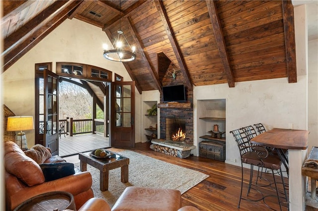 living area with a stone fireplace, wooden ceiling, beam ceiling, dark wood finished floors, and an inviting chandelier