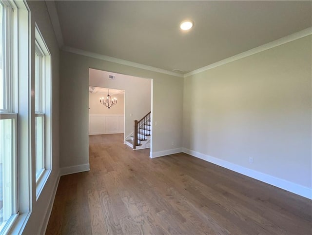 spare room featuring a wealth of natural light, crown molding, hardwood / wood-style floors, and a notable chandelier