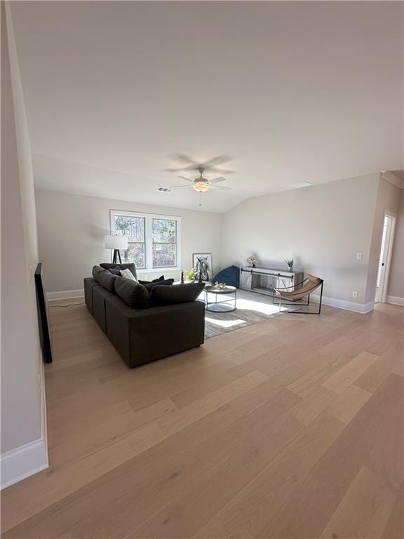 living room with ceiling fan, vaulted ceiling, and light wood-type flooring