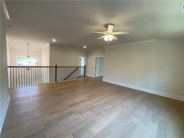 spare room featuring hardwood / wood-style flooring, ceiling fan with notable chandelier, and crown molding