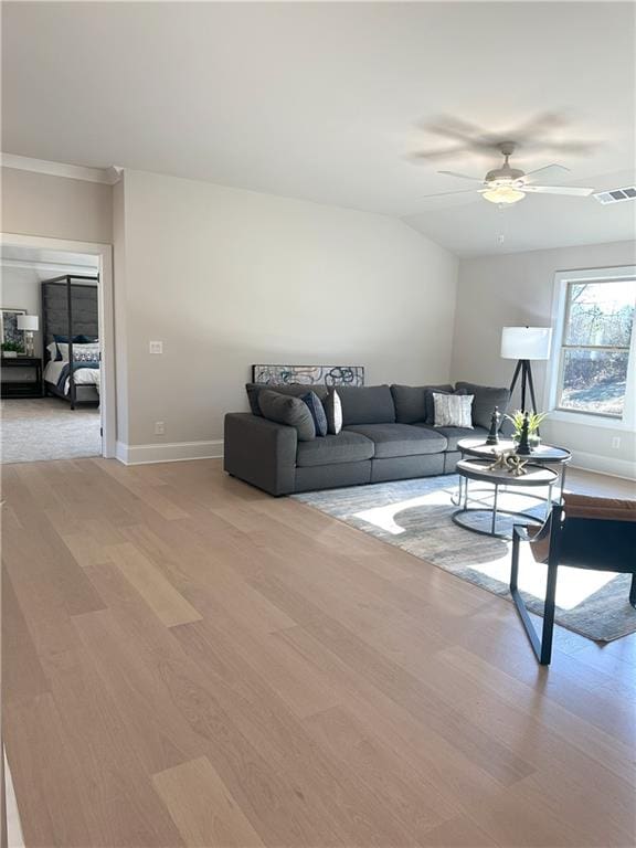 living room with ceiling fan, light hardwood / wood-style flooring, and vaulted ceiling