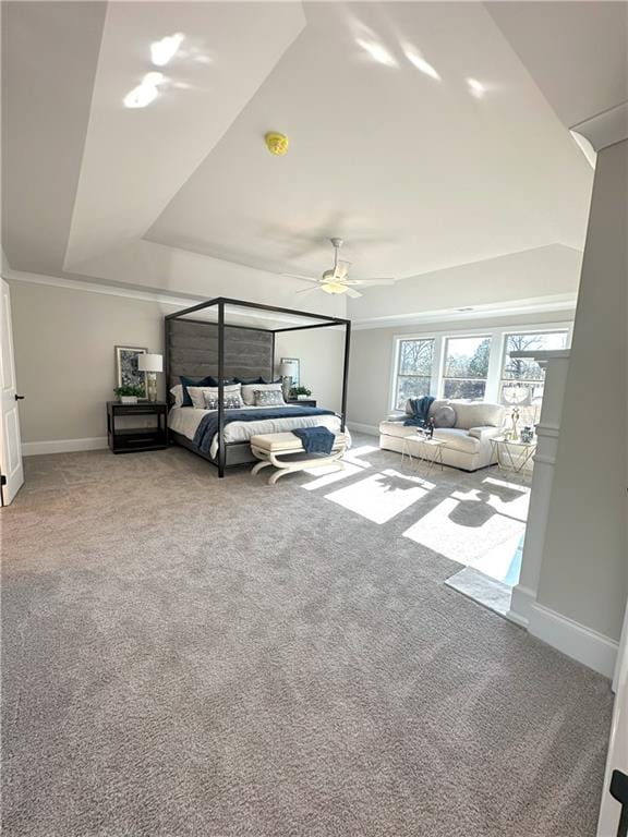 carpeted bedroom featuring a tray ceiling and ceiling fan