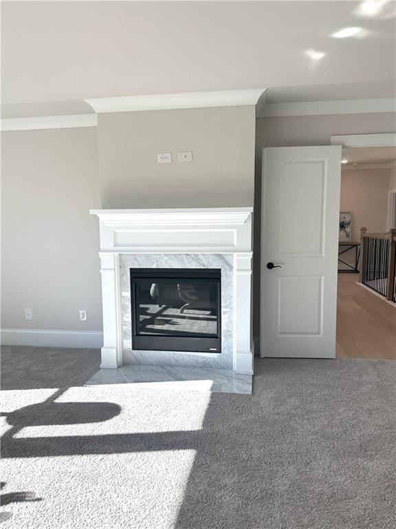 interior details featuring a premium fireplace, crown molding, and carpet floors